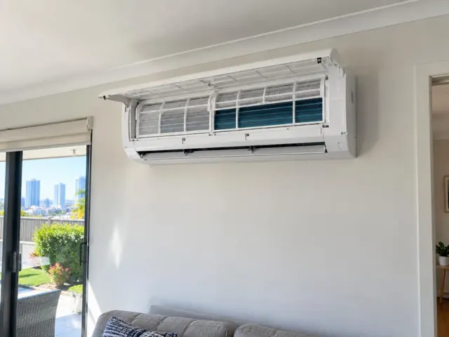 Clean split system with open front panel and visible filters on a white living room wall in Broadbeach