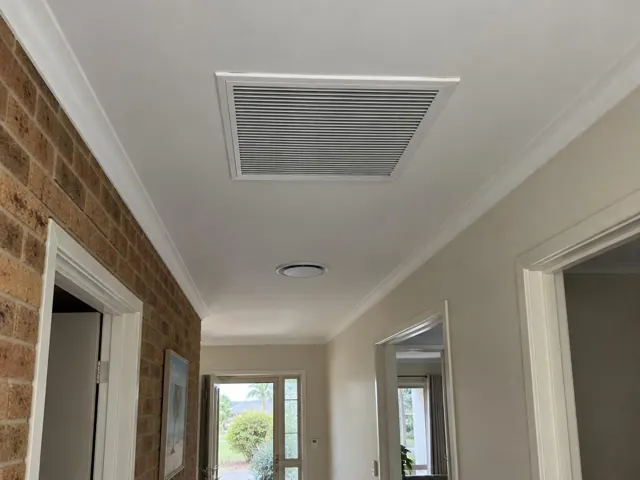 Ceiling return-air grille in a hallway with brick feature wall and doorways in Mermaid Beach